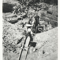 Lavage d'alluvions aurifères dans un sluice, par des chercheurs d'or isolés